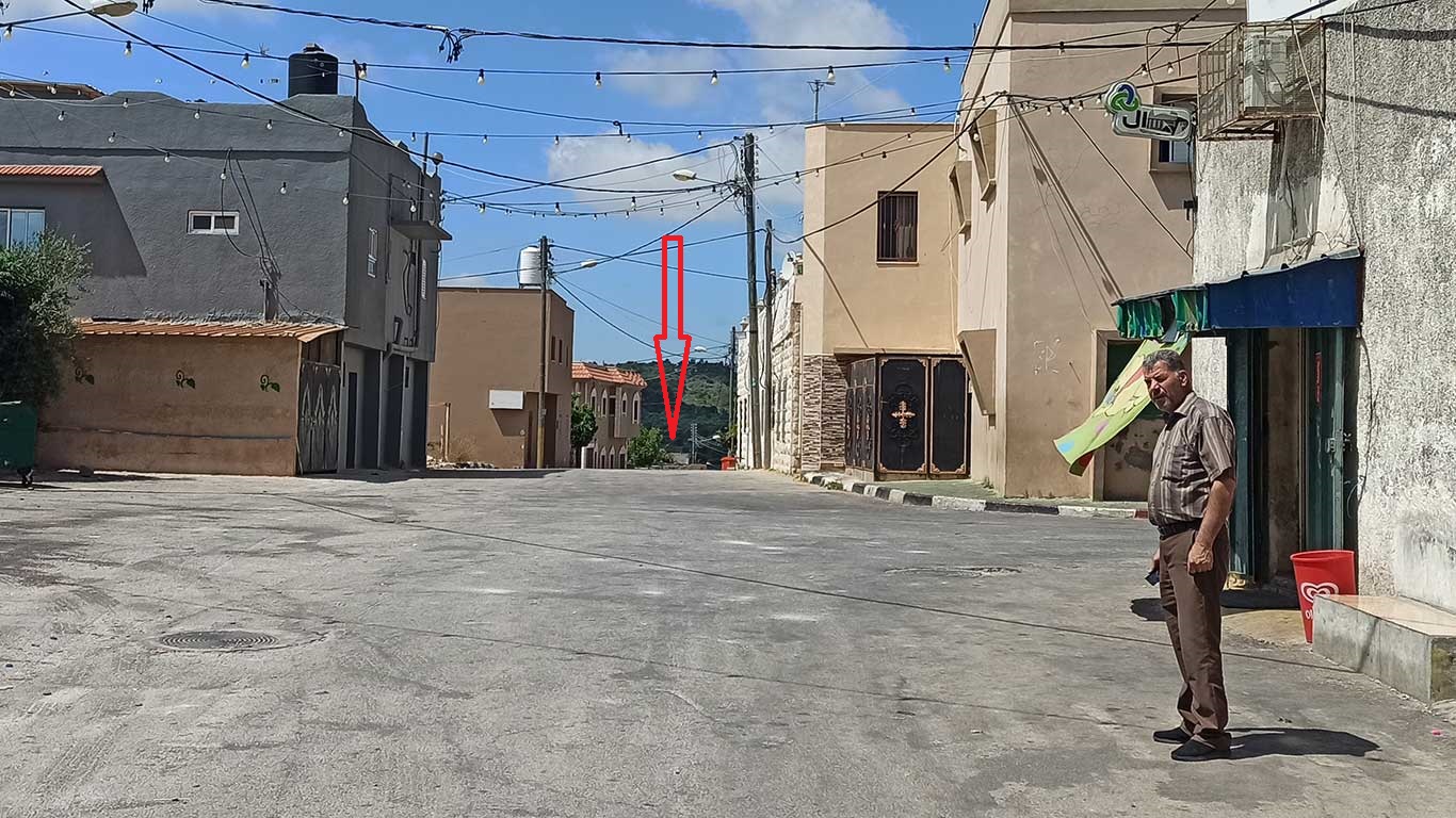 On the right, a man stands at the spot where Zidan was shot. On the left, down the street, the roof on which the soldiers stood. Photo by Abdulkarim Sadi, B’Tselem, 18 May 2021