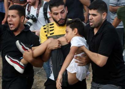 'Omar Abu a-Nil, shot in the neck by soldiers, being carried to an ambulance. Photo: 'Abd a-Rahim Khatib