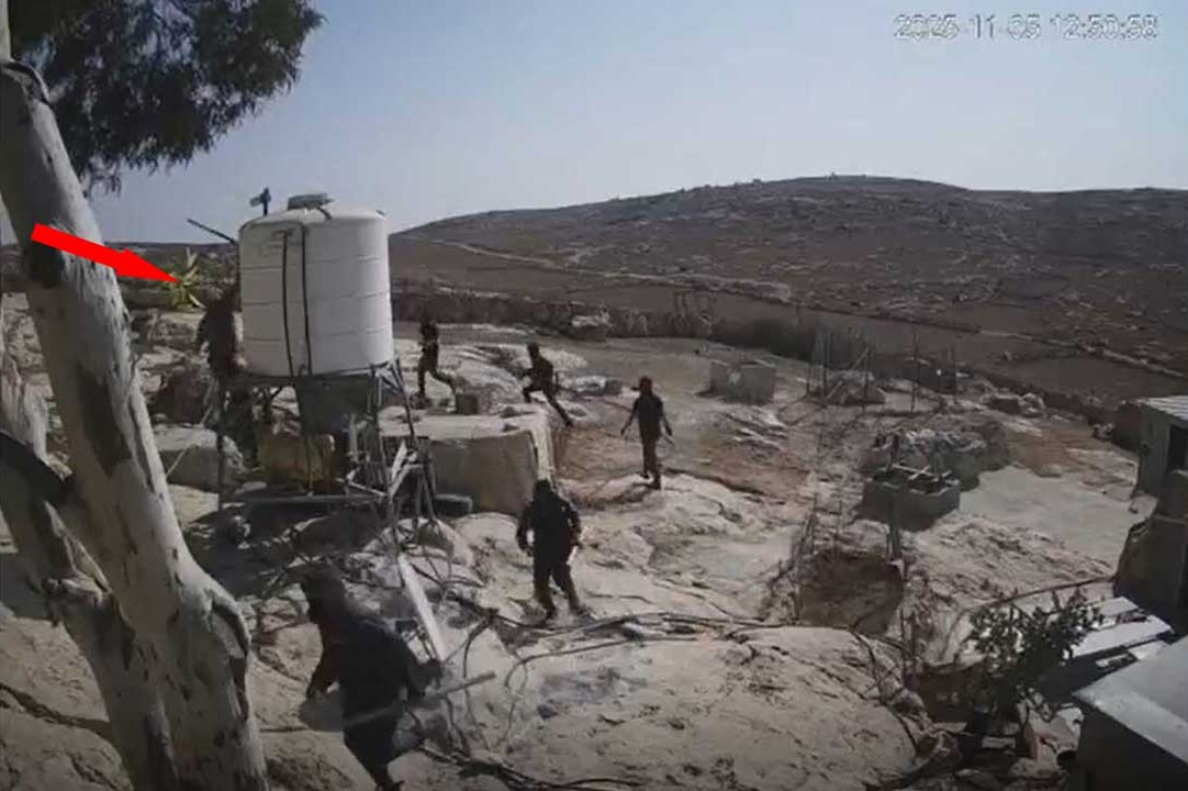 A settler smashing a security camera mounted on a water tank. Still from security camera footage
