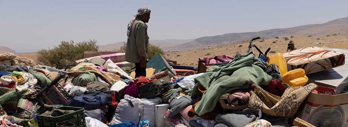 A resident of Khirbet Homsa al-Fuqa stands amidst the community's property, dumped by Israeli forces near 'Ein a-Shibli. Photo by Oren Ziv, ActiveStills, 7 July 2021