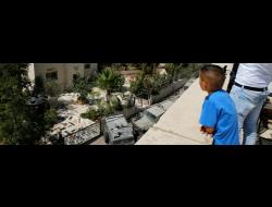 Palestinians watch the Israeli military arrive at the family home of the person who carried out the attack in the settlement of Har Adar. Photo by Ammar Awad, Reuters