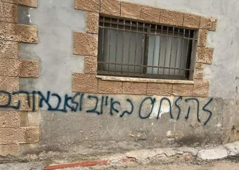 הכתובת: "להילחם באויב ולא באוהב" שריססו המתנחלים על  קיר אחד הבתים. התמונה באדיבות התושבים.
