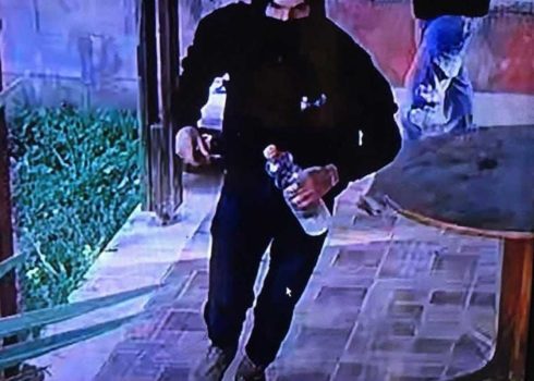 مستوطن ملثم يحمل زجاجة مواد قابلة للاشتعال في ساحة منزل في قرية جالود، 25.2.25. صورة قدمها السكان مشكورين.