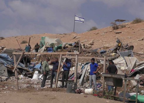 أنقاض بركسات السكن التي هدمتها الإدارة المدنية وأعلام بؤرة استيطانية فوقها. تصوير: عارف دراغمة، بتسيلم