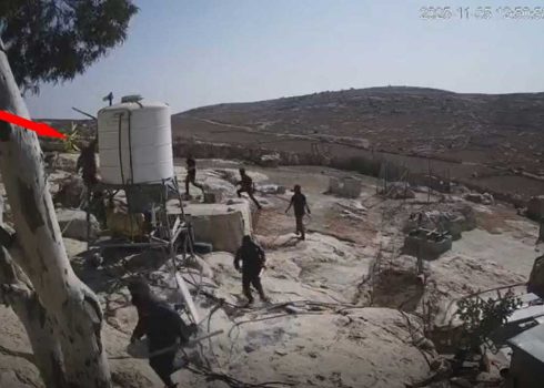 A settler smashing a security camera mounted on a water tank. Still from security camera footage