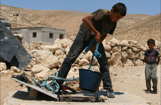 Palestinian boy drawing water from a cistern, Khirbet Jenbah, South Hebron Hills, 7 August 2012. Photo: B'Tselem. . צילום: שרון עזרן, בצלם
