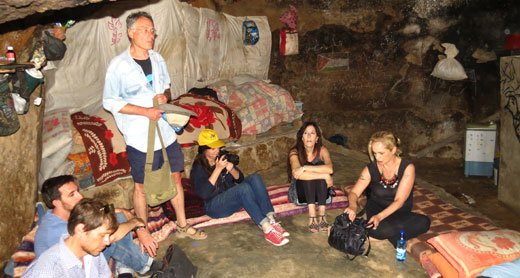 מימין לשמאל: הסופרים אלונה קמחי, צרויה שלו ואייל מגד במערת מגורים בכפר ח'ירבת ג'ינבה שבשטח האש 918 בדרום הר חברון. צילום גיא בוטביה