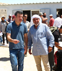 הסופר סייד קשוע על רקע בית ספר בכפר ח'ירבת ג'ינבה. צילום: גיא בוטביה